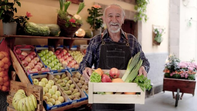Business food market: Asian senior seller working at local store holding wood box of vegetables outdoor - Retail and agriculture concept