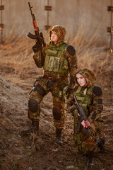 airsoft. A man and a woman in camouflage with machine guns in their hands on the ruins