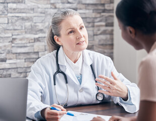 Making sure her patient understands every detail of the diagnosis. Shot of a doctor going through paperwork during a consultation with a patient in a medical office.