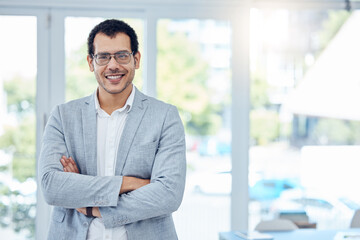 All in a days work. Shot of a young businessman folding his arms in a modern office.