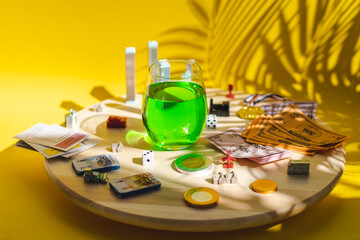 Plastic buildings, factories, playing cards, a winner medal and a glass of green drink on a round spinning board