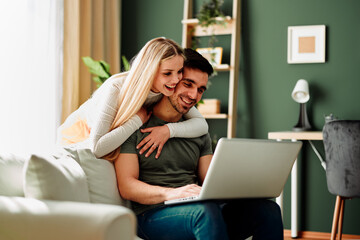 Fototapeta premium Beautiful young happy couple having video call via laptop at home