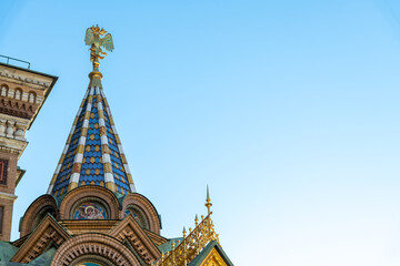 Golden double-headed eagle, coat of arms of Russia, on tower top of Church of the Savior on Spilled Blood in a sunny day in Saint Petersburg city. Clear blue sky. Copy space. National symbols theme.