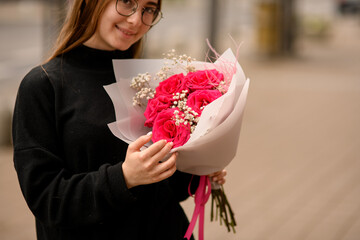 Closeup portrait of beautiful smiling brunette woman with red roses bouquet