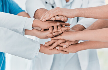 Improving patient outcomes together. Closeup shot of a group of medical practitioners joining their hands together in a huddle in a hospital.