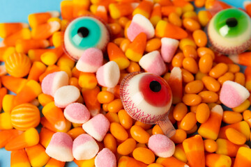Halloween candy on a bright blue background. corn and pumpkin coffees, marmalade.Halloween holiday background with jack o lantern pumpkin, candy corn and decorations.Top view.Flat lay. Place for text.
