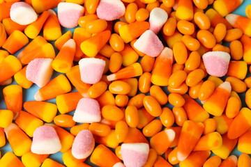 Halloween candy on a bright blue background. corn and pumpkin coffees, marmalade.Halloween holiday background with jack o lantern pumpkin, candy corn and decorations.Top view.Flat lay. Place for text.