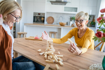 two senior women friends or sisters play leisure board game at home
