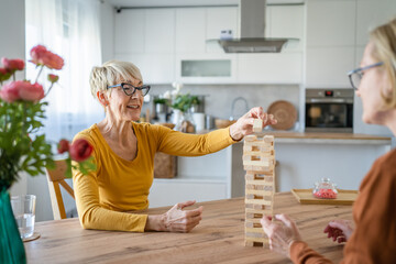 two senior women friends or sisters play leisure board game at home