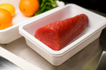 Closeup photo of large raw fresh ocean salmon fillet,, parsley, lemon and orange in two white trays