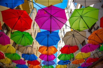 Fototapeta Ulica Piotrkowska w Łodzi i kolorowe parasole wiszące między budynkami nad błękitnym niebem. obraz