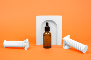 Brown bottle with a pipette on a beige background. Essential oil or serum and plaster figures on orange background