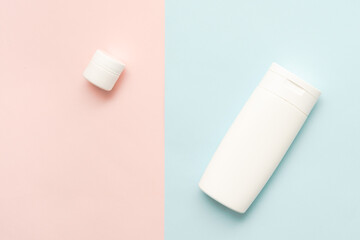 Flat lay of cosmetic bottles and tubes on two colored background