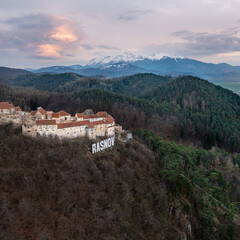 Fototapeta na wymiar Rasnov fortress and snowy Bucegi mountains in the spring at sunset 
