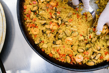 Traditional Paella in fry pan with rice, shrimp, mussels, vegetables and herbs.