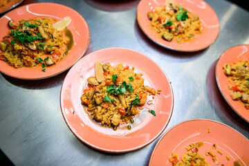 Many pink plates with Spanish dish Paella with meat, rice , seafood