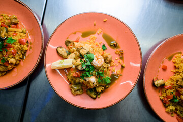 Top view on pink plates with traditional Spanish dish Paella with meat, rice , seafood