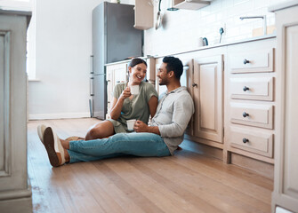 Laugh with me, stay with me. Shot of a young couple having a cup of coffee together at home.