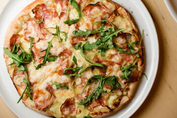 Ready-made mini pizza with jamon,ruccola covered with cheese on light table