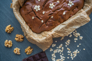 Oatmeal cake with bananas and walnuts on a dark grey background in home kitchen