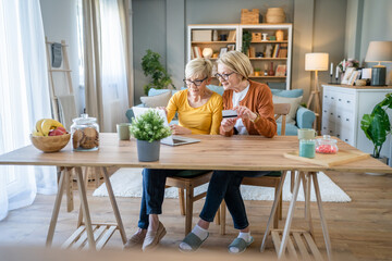Senior women two females hold credit card online shopping at home