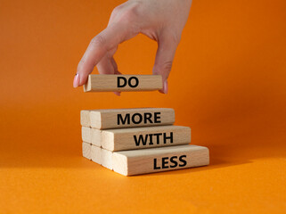 Do more with less symbol. Concept words Do more with less on wooden blocks. Beautiful orange...