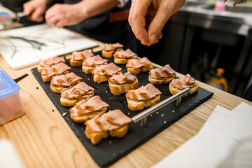 Close-up photo of chef hand sprinkles salt on bread pieces with meat