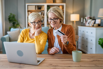 Senior women two females hold credit card online shopping at home