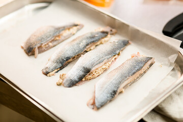 Four raw stuffed fish fillet decorated with chopped carrot. Side view