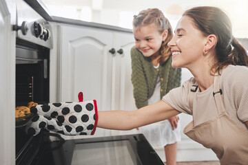 The smell of good cookies baking. Shot of a mother and daughter putting a tray of cookies in the...