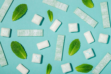 Different types of mint chewing gum and fresh mint leaves on a blue background top view