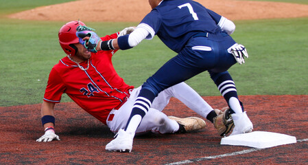 Baseball player sliding into thier base trying to avoid the tag