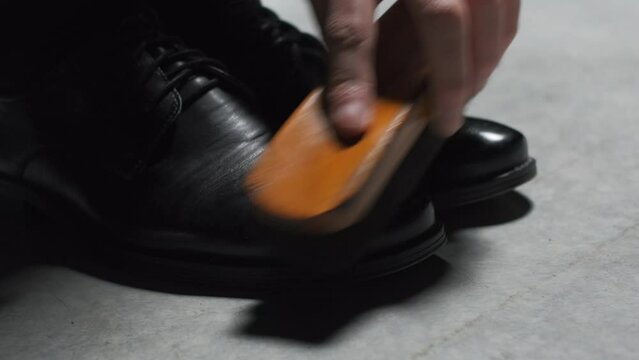 Waxing leather black classic shoes. Stock footage. Close up of cleaning and polishing boots.