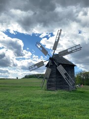 Fototapeta na wymiar Ukrainian traditional wooden windmill on a green field with a blue sky