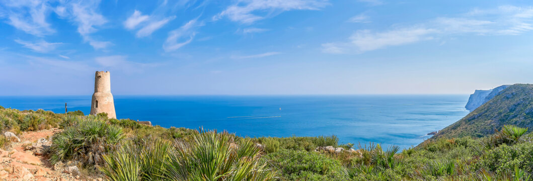 Torre del Gerro in Denia, with the Cabo San Antonio and Mediterranean sea as a backdrop on a clear and sunny day. In Denia, Alicante, Spain