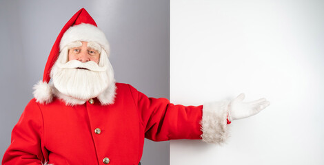 Santa claus points to an empty space. Christmas advertisement.
