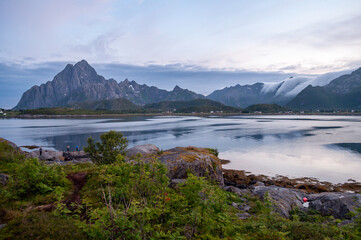 Sunset in the evening during the polar night in Norway. Sea and high rocky mountains with clouds.