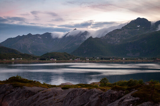 Sunset in the evening during the polar night in Norway. Sea and high rocky mountains with clouds.