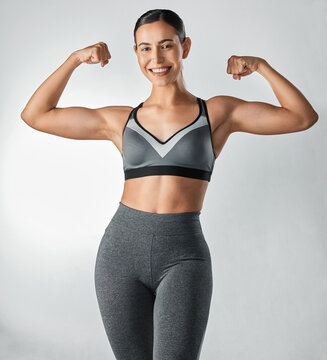 Dont be afraid to show it off. Studio portrait of a sporty young woman flexing her arms against a grey background.