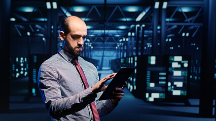 Information security officer working in data center with tablet, analyzing server rack cabinets in render farm. IT support specialist inspecting cloud computing system, ai concept. Tripod shot.