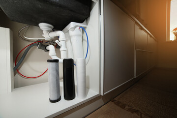 House water filtration system to drinkable condition, reverse osmosis. Installation or replacement filter cartridges of foamed polypropylene, granular, briquettes carbon under kitchen sink with lights