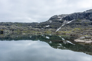 Reflection over a lake in moody vibe in the hike for Trolltunga,  Norway
