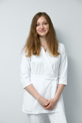 Portrait of cheerful young caucasian brunette female biologist in white robe looking and smiling at camera with arms crossed isolated over white background. Medicine concept.