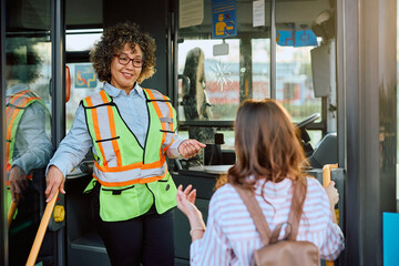 Happy female bus driver talks to passenger at station. - obrazy, fototapety, plakaty