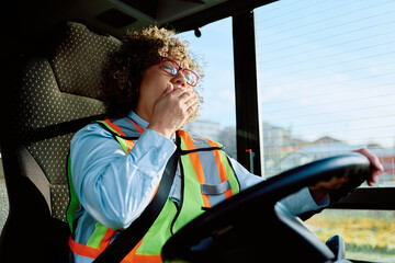 Tired female driver yawning while driving bus.