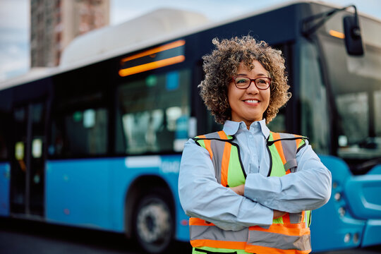 Proud female bus driver at station looking away.