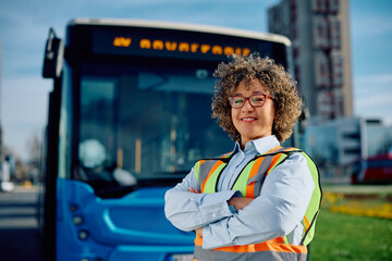 Happy female bus driver with crossed arms looking at camera.