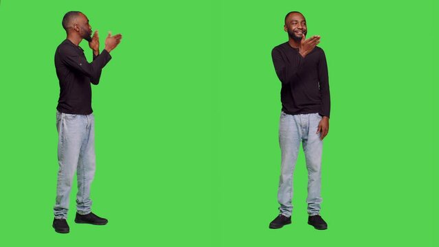 African american man sending air kisses on camera, posing with kissy face on full body greenscreen. Young adult being romantic in studio and doing flirty gesture, optimistic reaction.