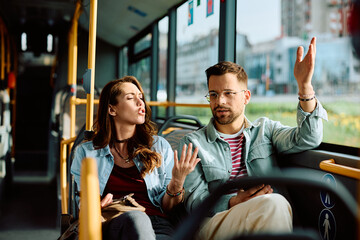 Young couple arguing while riding in bus.