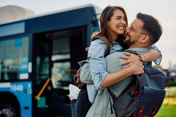 Young cheerful couple embracing at bus station. © Drazen
